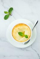 cup of coffee with foam and a sprig of mint on a marble background top view photo