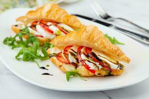 croissants with cheese, vegetables, cherry tomatoes and herbs photo