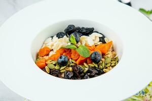 deep plate with cereals, berries, pistachios, dried apricots and raisins top view photo