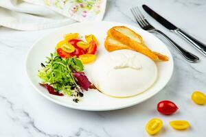 mozzarella with spinach, cherry tomatoes, wild berries and bread in a round plate side veiw photo