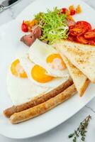 scrambled eggs with vegetables, cherry tomatoes, bread, herbs and sausages on a white plate side view photo