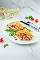 croissants with cheese, vegetables, cherry tomatoes and herbs photo