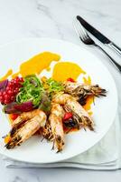 cooked shrimp with herbs and berries on a white plate, side view photo