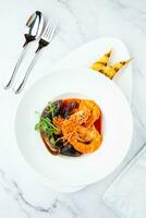 cooked shrimp with herbs and mussels on a white plate, top view photo