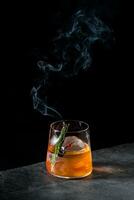 aromatic cocktail with a sprig of pine needles and round ice on a dark background, side view photo