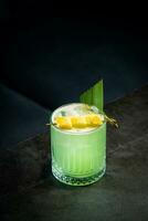 lime coctail with pineapple pieces and cinnamon side view photo