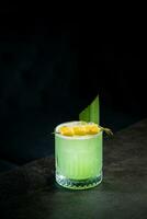 lime coctail with pineapple pieces and cinnamon side view photo