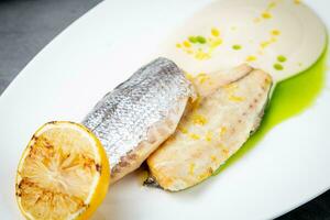 pieces of fried fish with sauce and fried lemon on a white plate side view photo