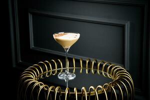 iced latte with foam in a martini glass on a dark background photo