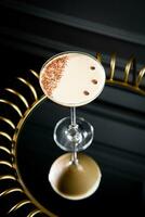 iced latte with foam in a martini glass on a dark background photo