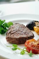 beef steak with grilled vegetables and herbs on a light background photo