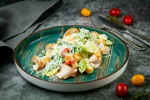 side view of caesar salad with cheese on a blue plate photo