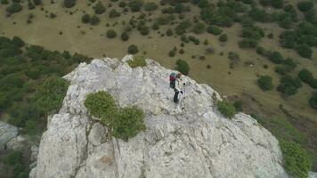 wandelaar vrouw is staand Aan top van rotsachtig berg. antenne visie. video
