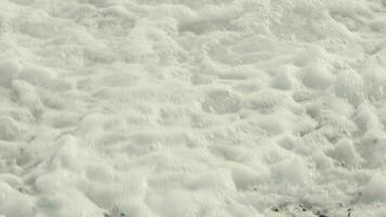 salpicaduras mar olas con espuma son laminación en Guijarro costa. de cerca vista. video
