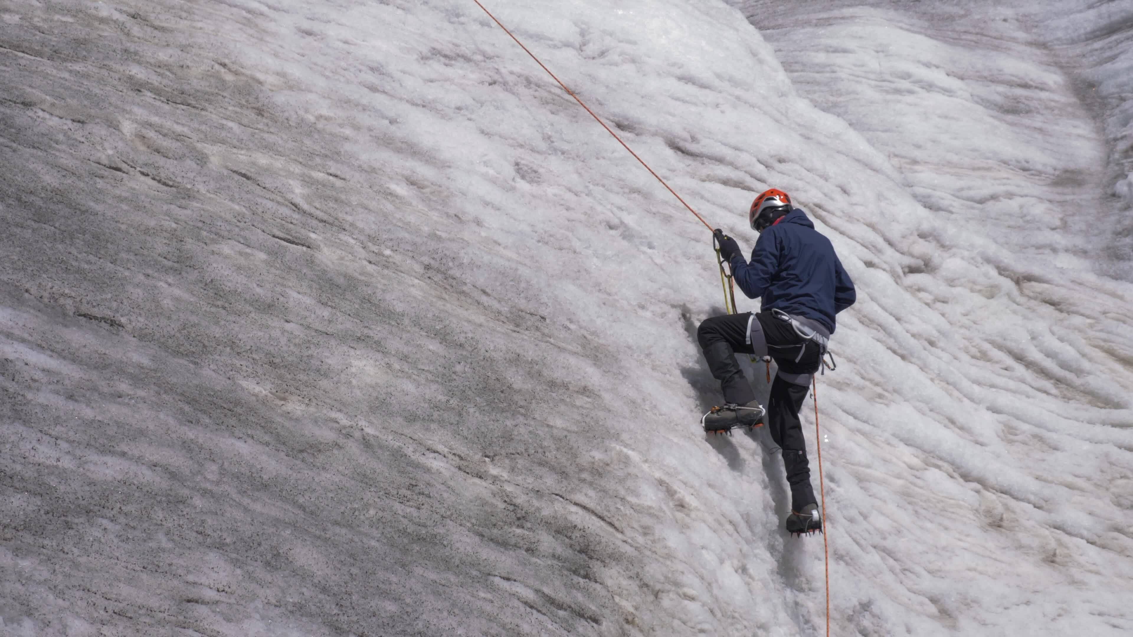 alpiniste homme dans crampons est en utilisant jumar sur fixé corde à monter sur raide neigeux