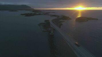 atlântico oceano estrada dentro Noruega às verão ensolarado pôr do sol. carros estão passagem em lojas ponte. aéreo visualizar. revelar tomada. zangão é vôo avançar, Câmera é inclinação acima video