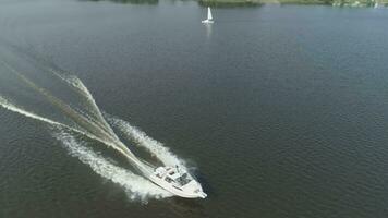 luxe la vitesse moteur bateau est courses dans le mer à ensoleillé journée. aérien voir. drone est en volant autour bateau et Ascendant, caméra est basculant bas. projecteur coup video