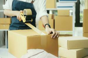 Online entrepreneur using scotch tape to seal parcel box. photo