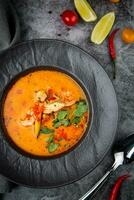 tom yam soup with chicken, lime, cherry tomatoes and parsley top view photo
