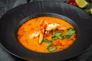 tom yam soup with chicken, lime, cherry tomatoes and parsley side view photo