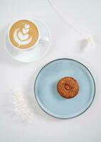 Cookies with nuts inside and coffee with a pattern on a round plate top view photo
