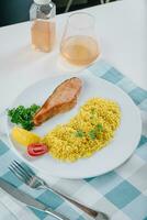 proper nutrition, daily diet, weight loss. greens, tomatoes, salmon steak with lemon and couscous garnish on a plate. Top view photo