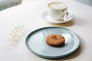 Cookies with nuts inside and coffee with a pattern on a round plate top view photo