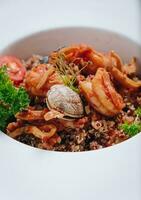 buckwheat with seafood, oyster, tomato and herbs in a deep plate side view photo