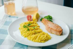 proper nutrition, daily diet, weight loss. greens, tomatoes, salmon steak with lemon and couscous garnish on a plate. Top view photo