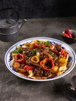 noodles with bell pepper, potatoes, meat and herbs in a plate with a pattern side view photo