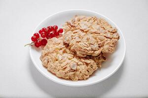whole grain cookies with a sprig of red currants in a small white plate side view photo