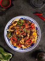 tallarines con campana pimienta, papas, carne y hierbas en un plato con un modelo parte superior ver foto