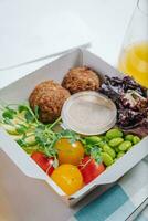 bowl in Chinese style.meatballs with beans, herbs, cherry tomatoes and sauce in a container photo