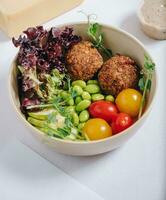 bowl in Chinese style.meatballs with beans, herbs, cherry tomatoes and sauce in a bowl photo