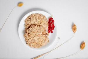 whole grain cookies with a sprig of red currants in a small white plate top view photo