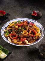 noodles with bell pepper, potatoes, meat and herbs in a plate with a pattern side view photo