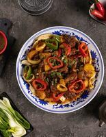 noodles with bell pepper, potatoes, meat and herbs in a plate with a pattern top view photo