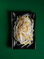 fresh and raw bean sprouts on a black plate. View from above. Chinese cuisine, ingredient for hotpot photo