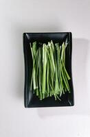 full green onion on a black plate. View from above. Chinese cuisine, ingredient for hotpot photo