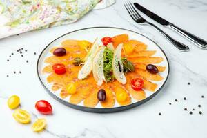 Pieces of smoked red trout with tomatoes, feta cheese, herbs. Mediterranean appetizer, top view photo