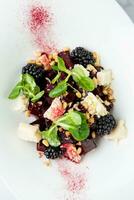 salad of blackberries, beets, seeds and cheese, side view on a white plate photo