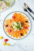 Pieces of smoked red trout with tomatoes, feta cheese, herbs. Mediterranean appetizer, top view photo