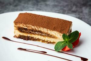 esponja pastel lleno con fresas, menta y chocolate jarabe en un blanco plato lado ver foto