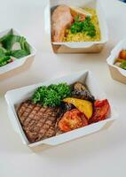 food in containers. proper nutrition, daily diet, weight loss. drink, veal steak with grilled vegetables, salmon steak with couscous side dish. Top view photo