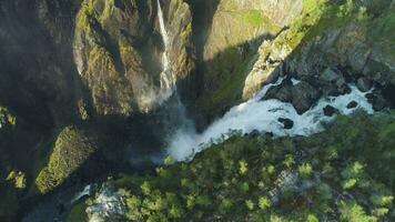 voringfossen vattenfall och klippor med grön träd i Norge på solig sommar dag. antenn se. Drönare är kretsande runt om video