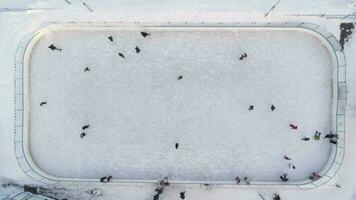 persone siamo pattinando su ghiaccio pista nel il soleggiato giorno. aereo verticale dall'alto al basso Visualizza. stabilendo sparo. fuco è volante verso il basso.. video