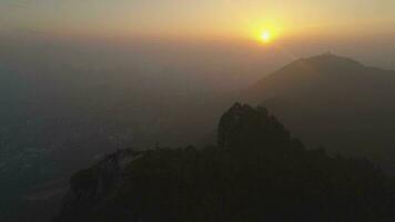 Lion Rock and Hong Kong Skyline in Smog at Sunset. Aerial View. Drone is Flying Forward and Upward, Camera is Tilting Down. Establishing shot video