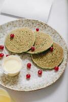 pancakes with berries and a glass of juice on a light background photo