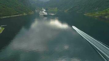 motor velocidad barco y grande crucero revestimientos en geiranger fiordo. Noruega. aéreo revelar vista. zumbido moscas adelante, cámara se inclina arriba video