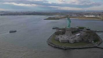 statua di libertà a nuvoloso giorno. libertà isola, nuovo York città. aereo Visualizza. largo sparo. orbitante video